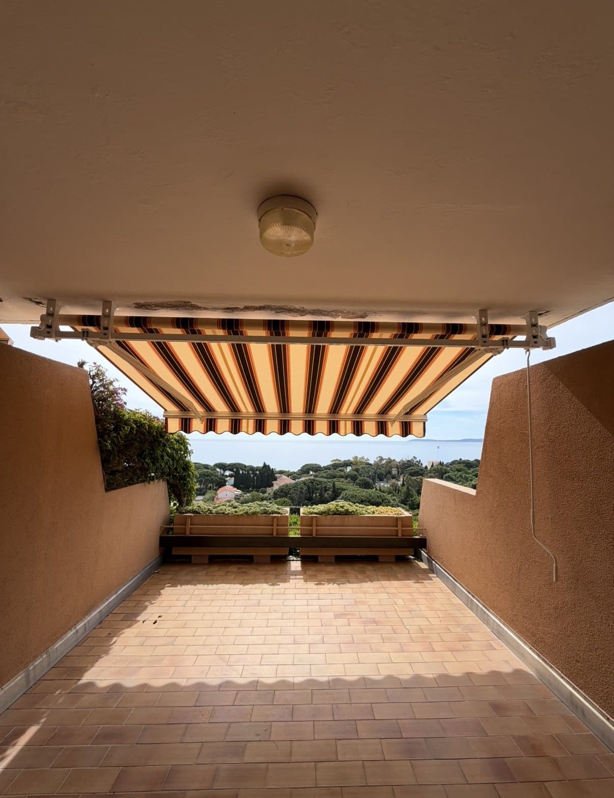 Banne rayée déployée sur une terrasse avec vue sur la mer