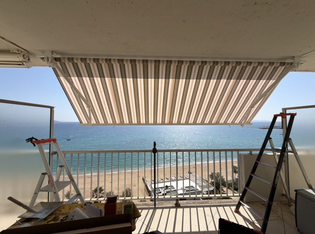 Banne rayée déployée sur un balcon face à la plage et à la mer