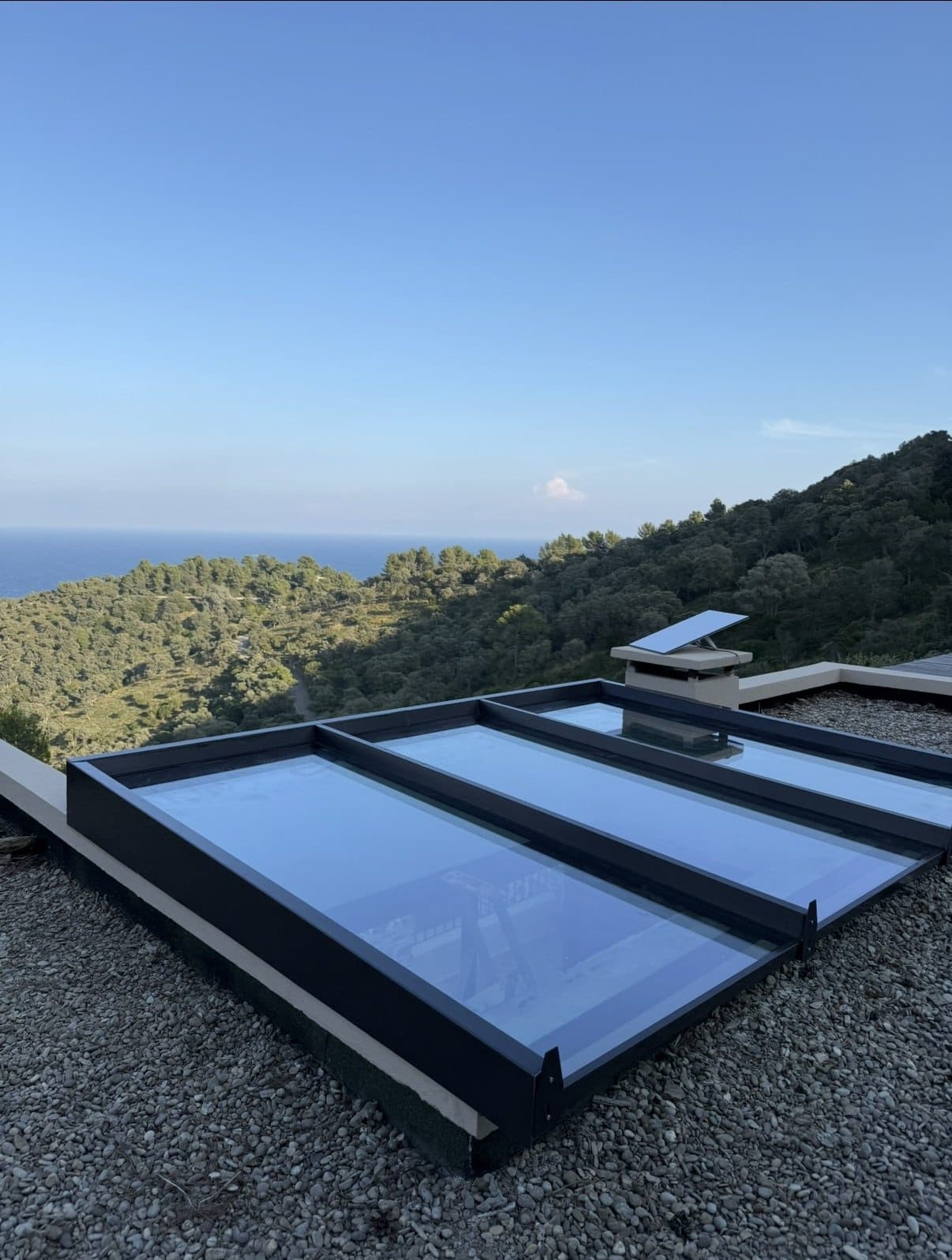 Verrière de toit en aluminium et verre posée sur une toiture-terrasse avec vue sur la mer et les collines du Var